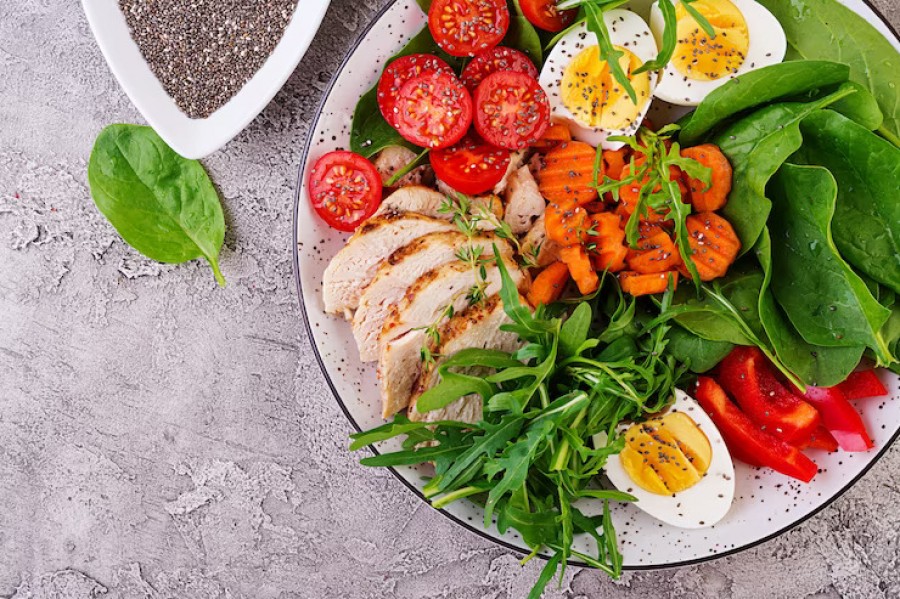 Hands arranging fresh herbs near a bowl of salad